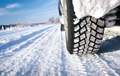 Close up of snowy wheels driving on a snow covered road