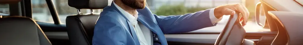 Short bearded man driving a car in a suit